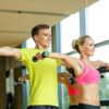 smiling man and woman with dumbbells in gym